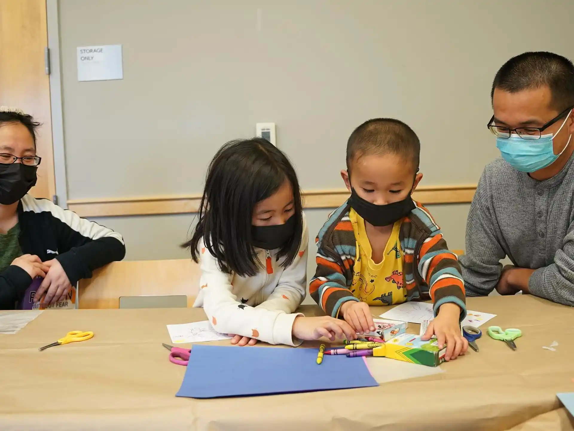 a group of children sitting at a table with a blue board