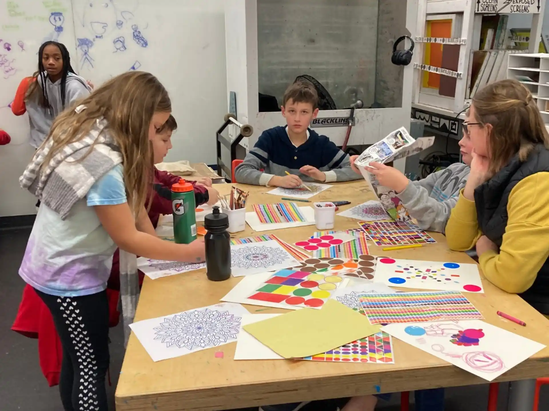 a group of people sitting at a table with colorful paper on it