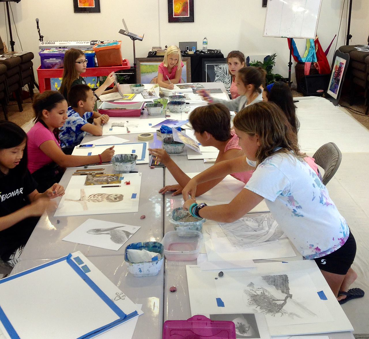 a group of children sitting at a table with drawings on it