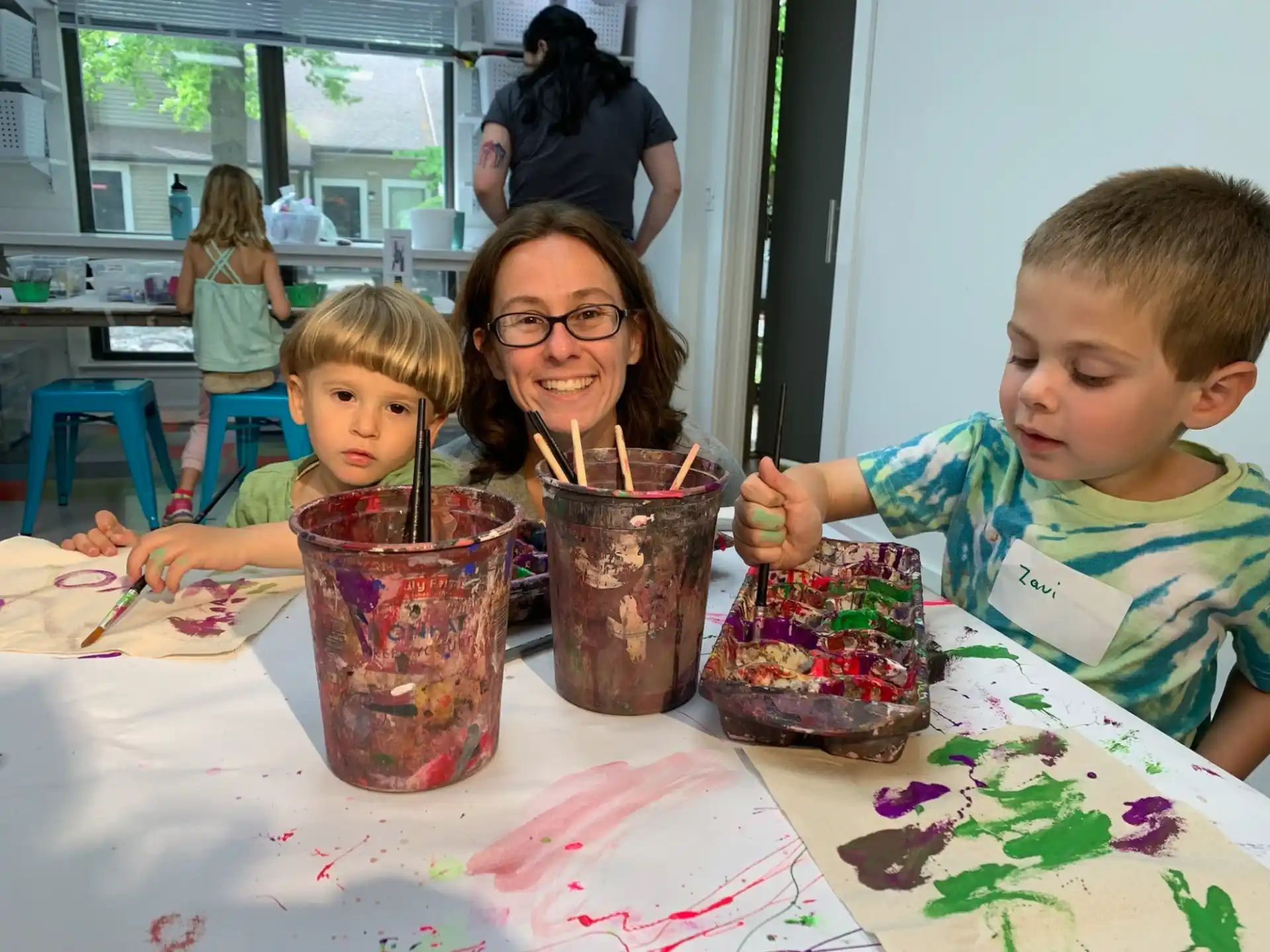 a person and two children sitting at a table with food and drinks