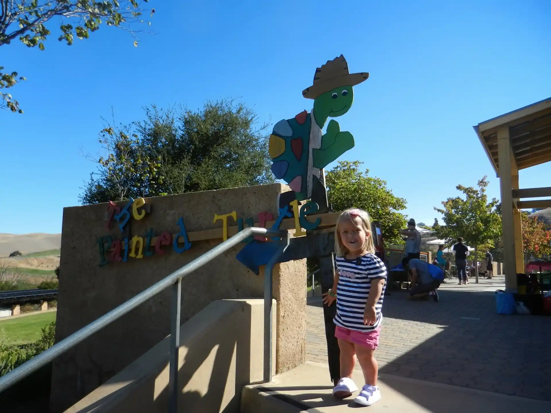 a girl standing on a concrete wall with a cartoon character on it