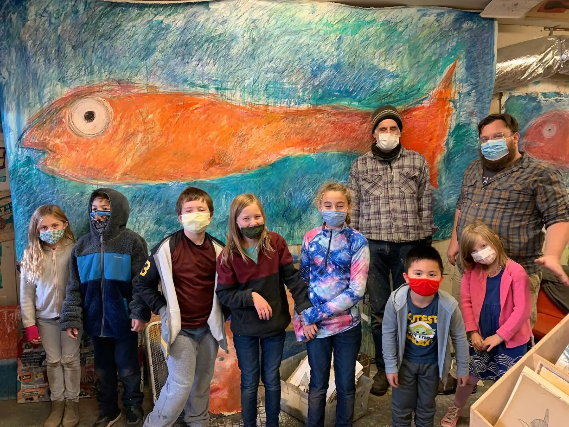 a group of people posing for a photo in front of a painting