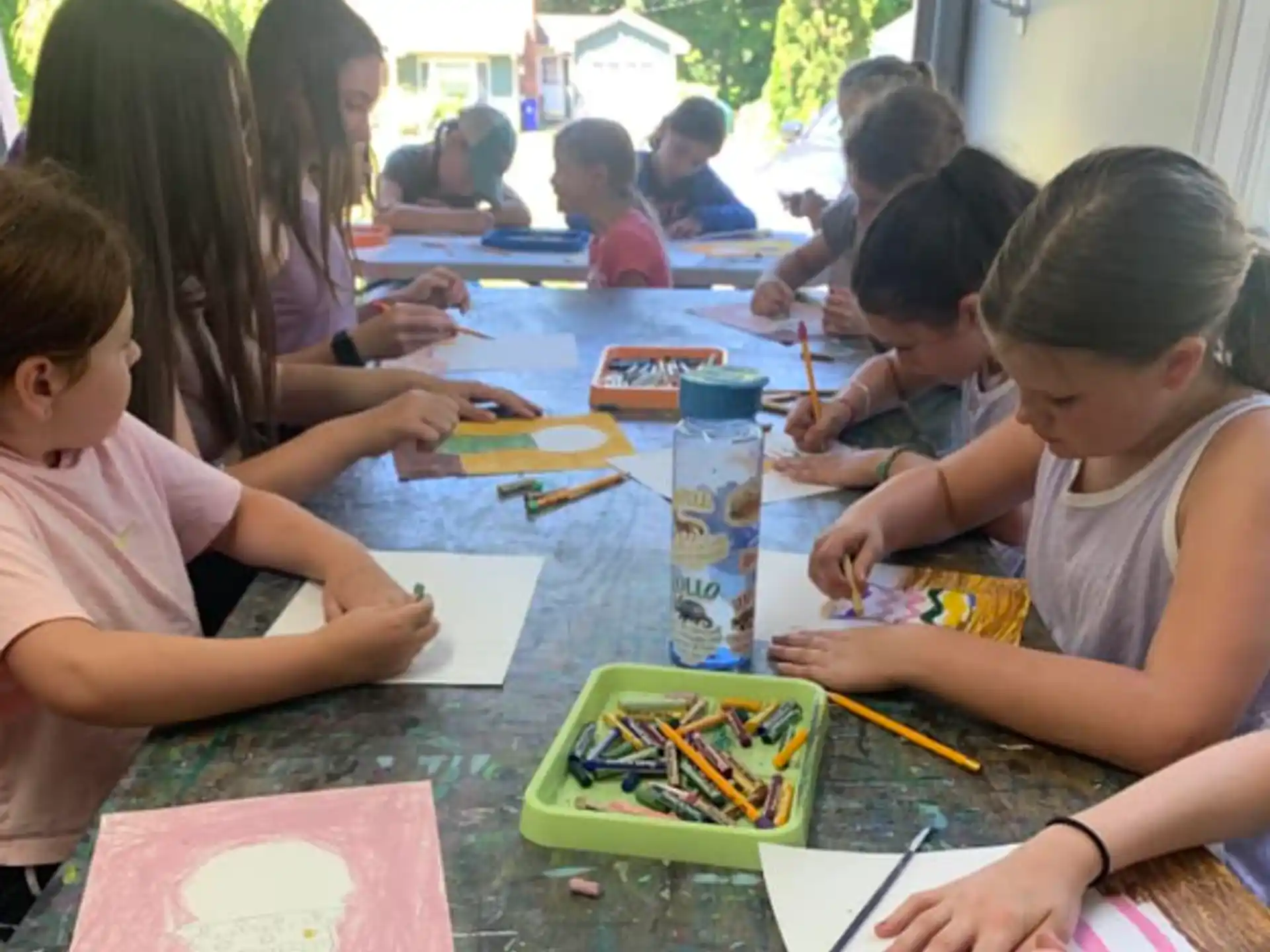a group of children sitting at a table painting