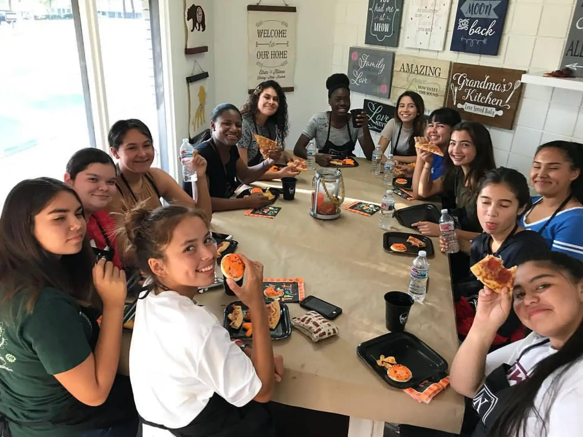 a group of people sitting at a table eating pizza