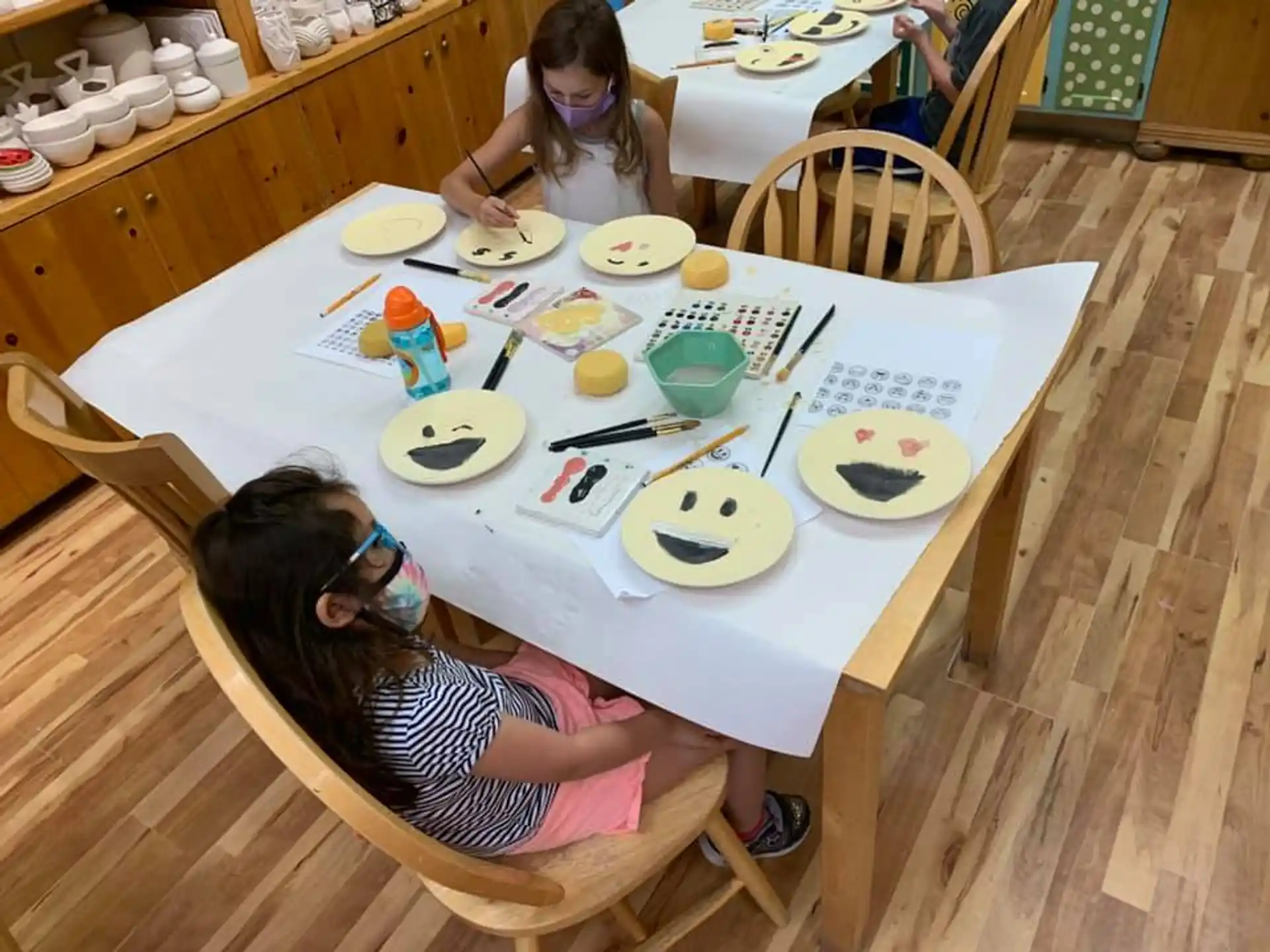 a group of girls sitting at a table with plates and bowls