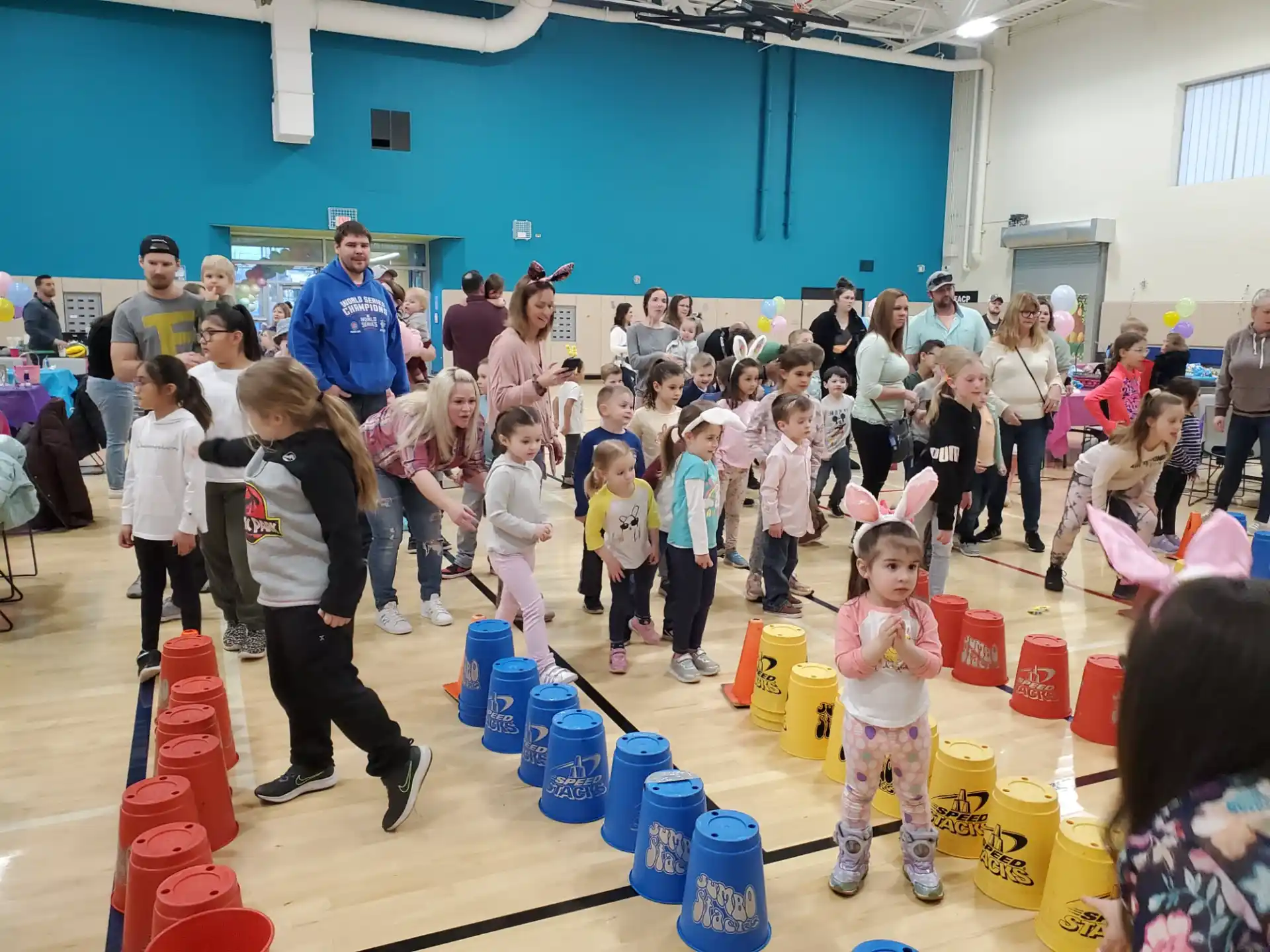 a group of people standing around a table with many plastic cups on it