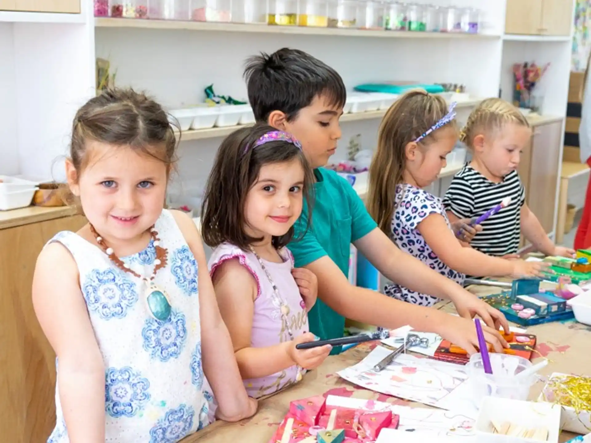 a group of children sitting at a table with a cake