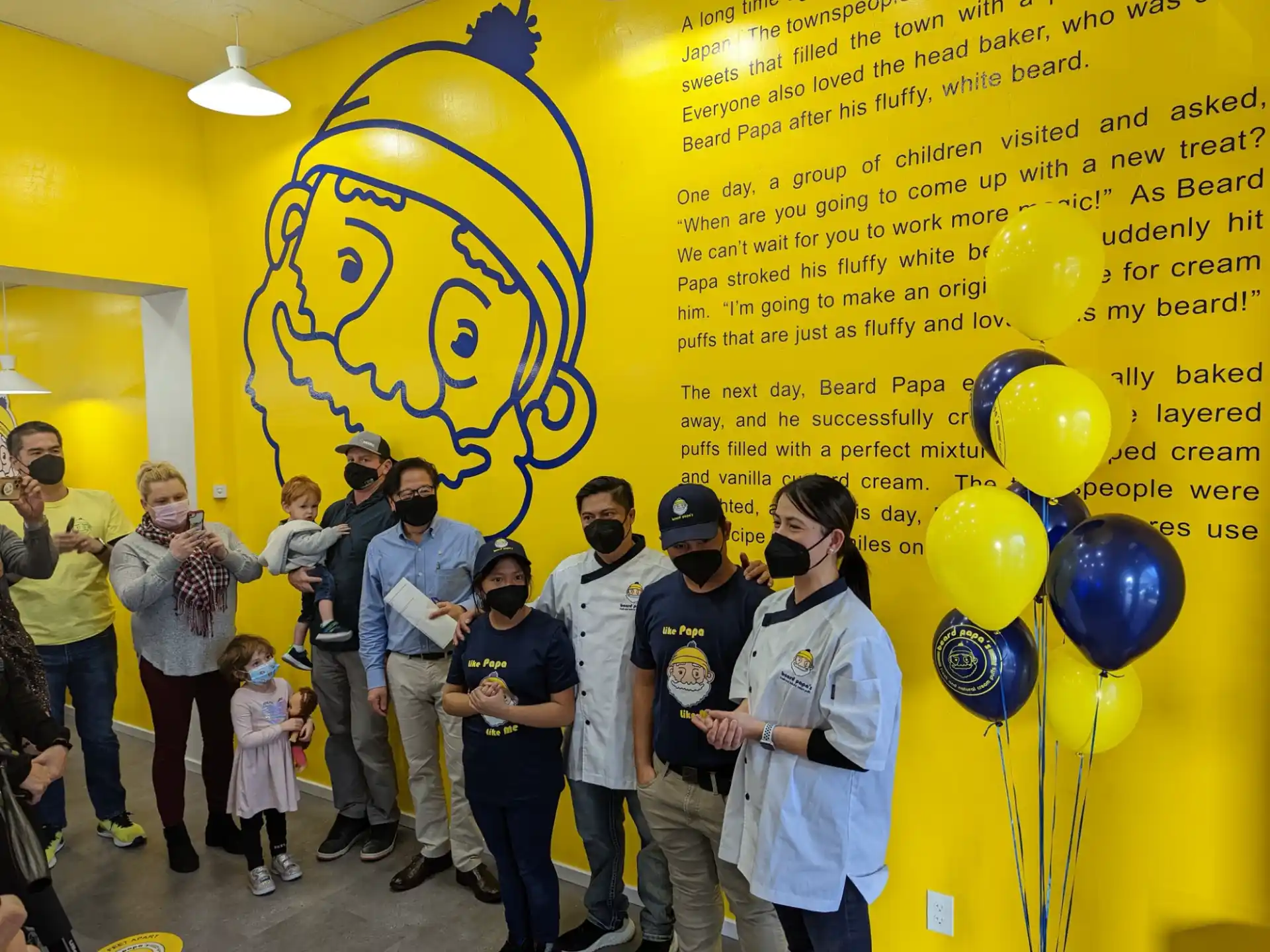 a group of people standing in front of a wall with balloons