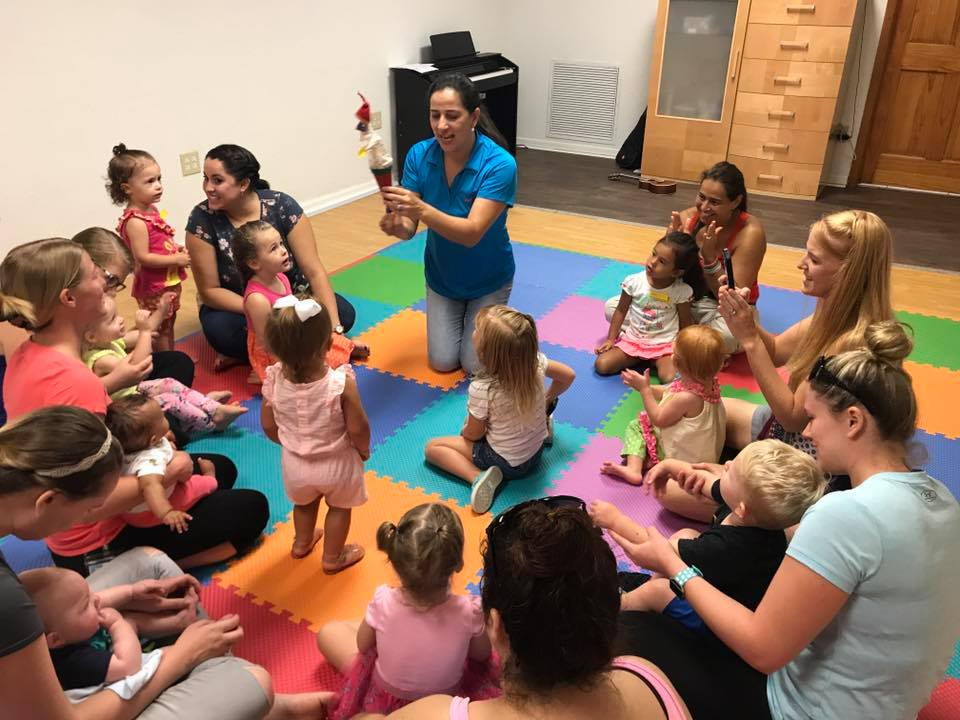 a person standing in front of a group of children sitting on the floor