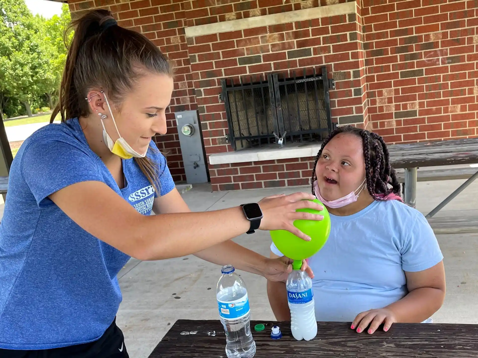 a person and a girl sitting at a table with water bottles