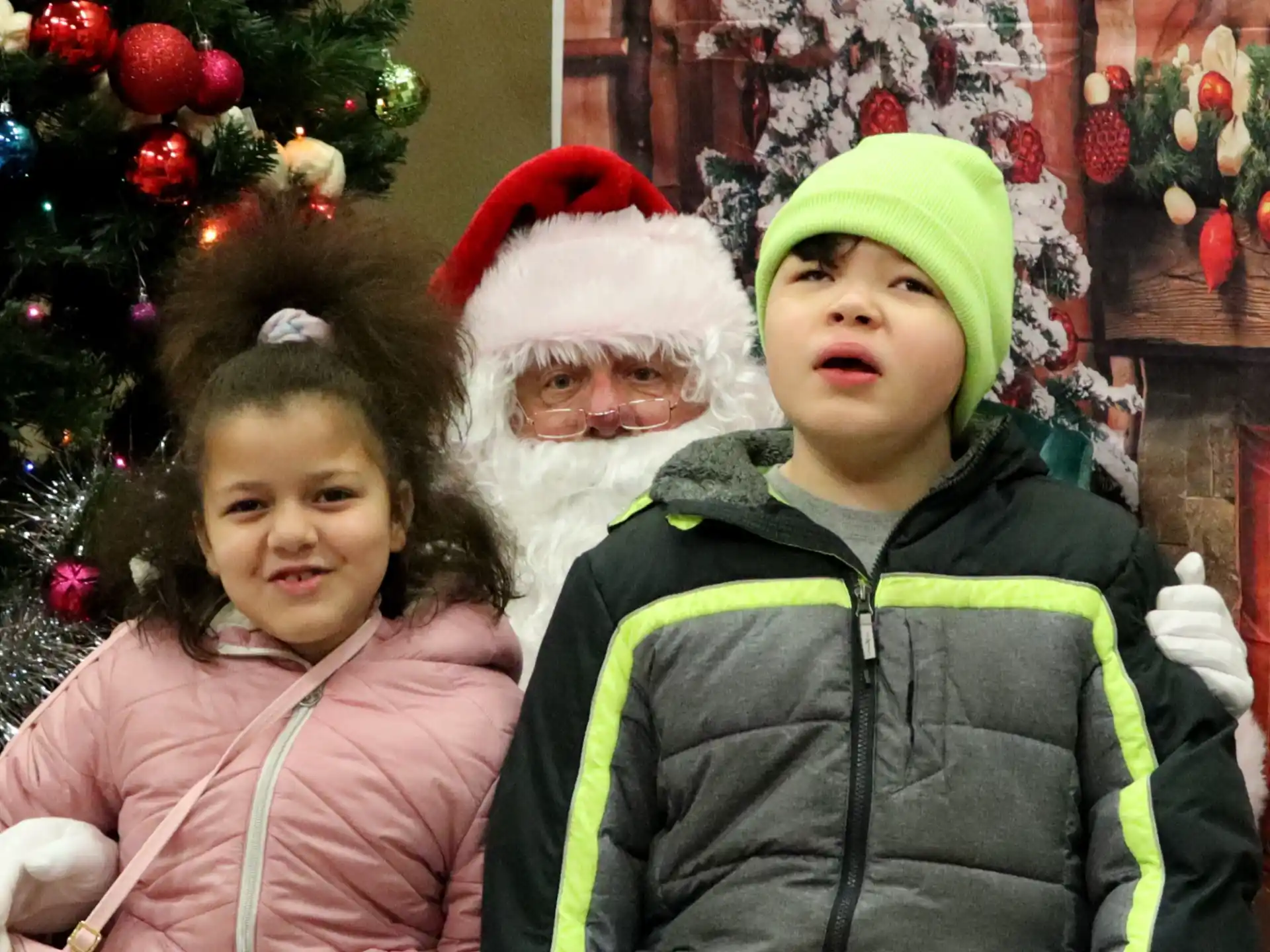 a person and a girl standing in front of a christmas tree