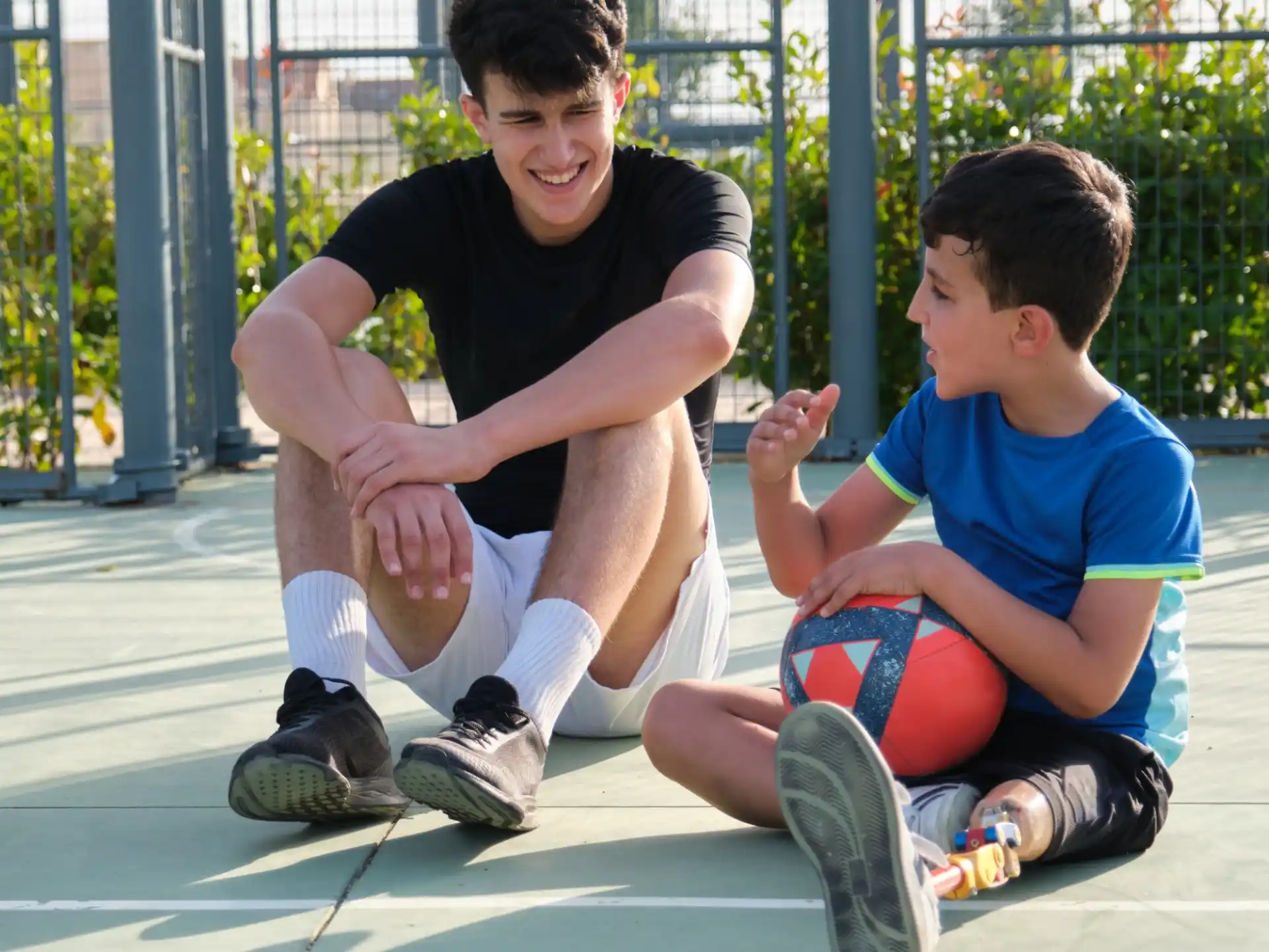 a person kneeling next to a boy kneeling on the ground