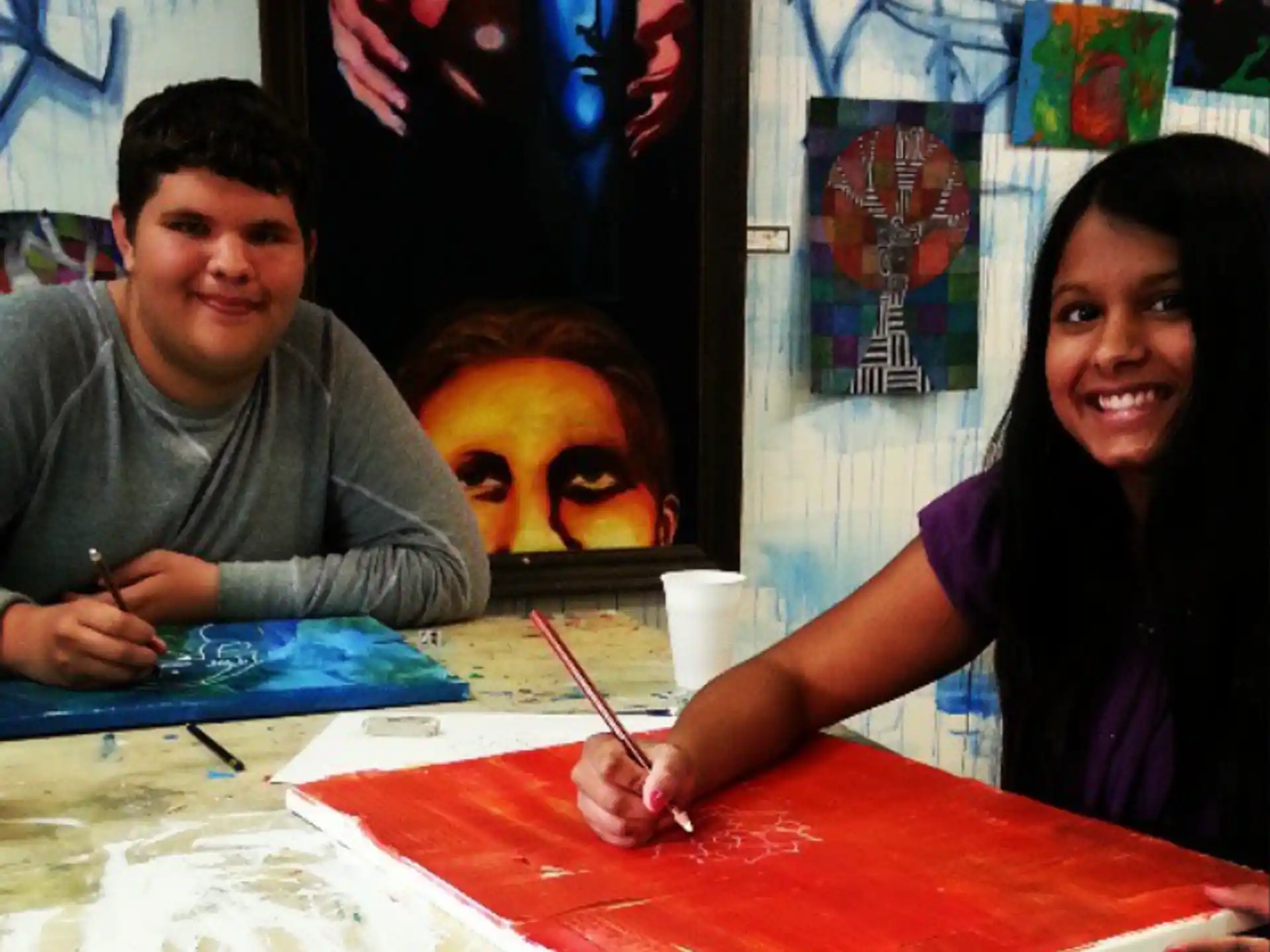 a man and a woman sitting at a table with a painting