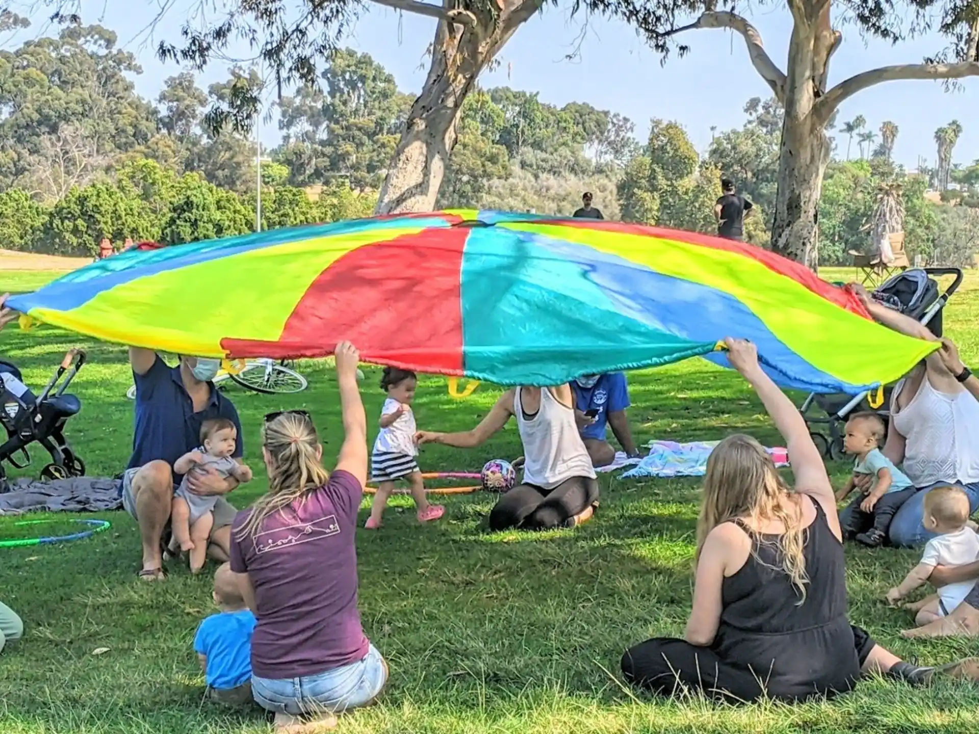 a group of people sitting on the grass holding a large yellow and blue flag