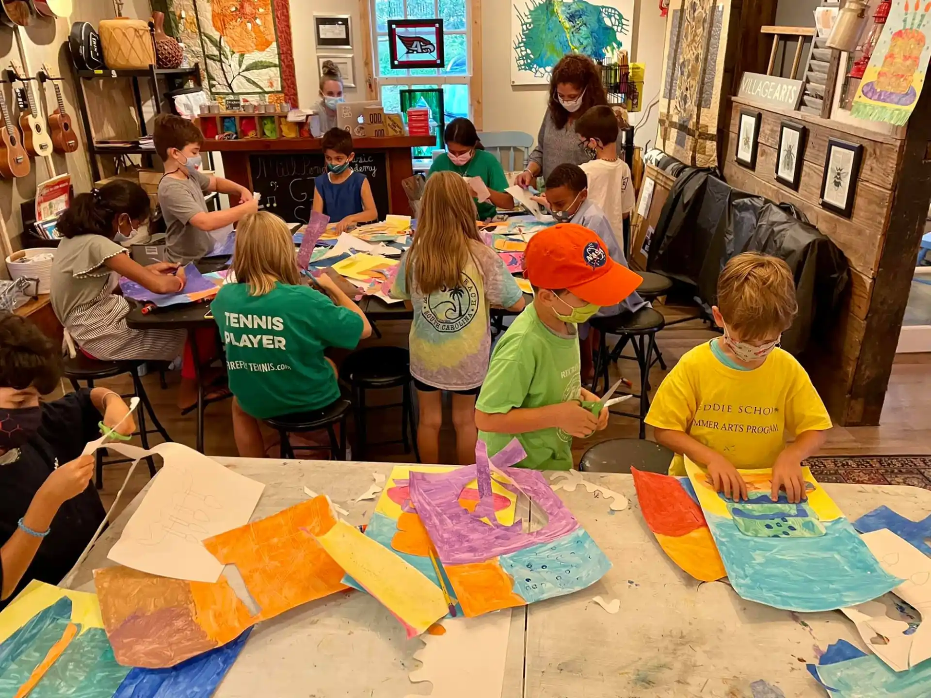 a group of children sitting at a table painting