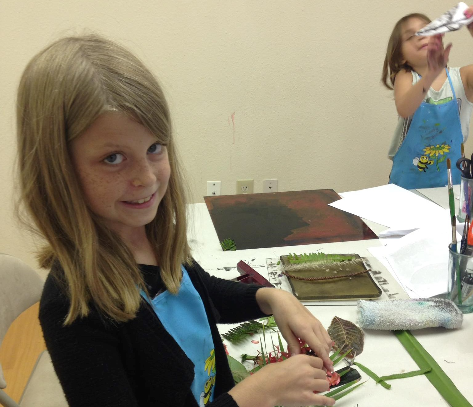 a woman sitting at a table with a plant and a girl standing behind her