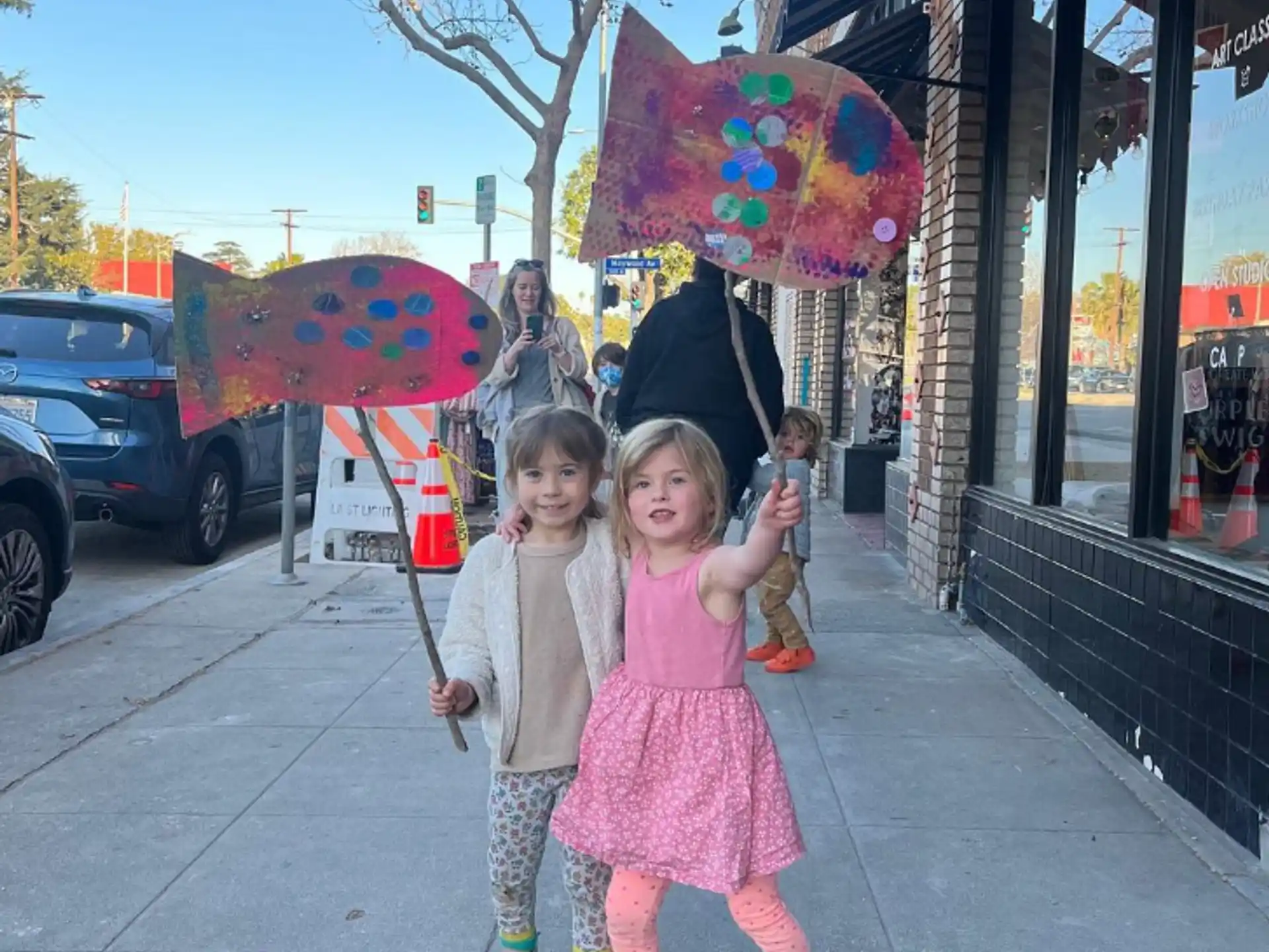 a couple of girls stand under an umbrella