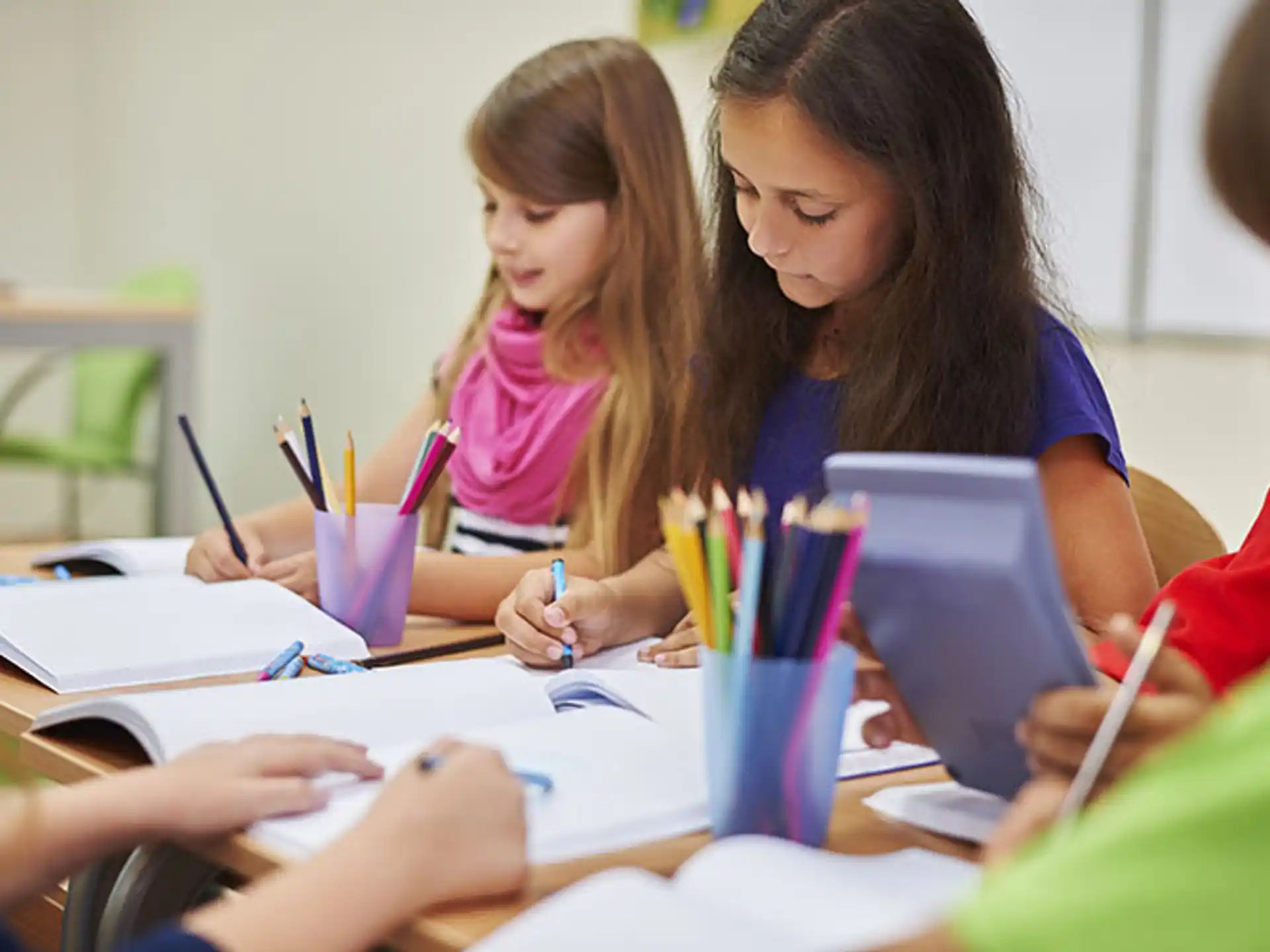 a group of children sitting at a table writing on paper