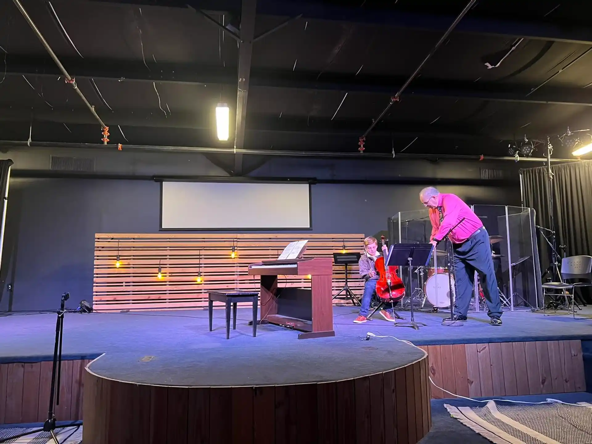 a man playing a guitar on a stage with a woman playing drums
