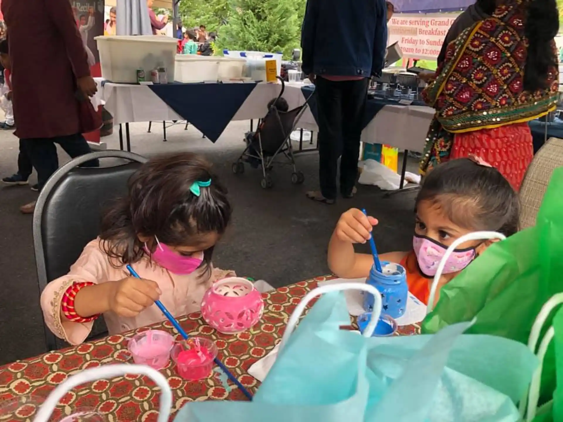a couple of young girls sitting at a table with cupcakes
