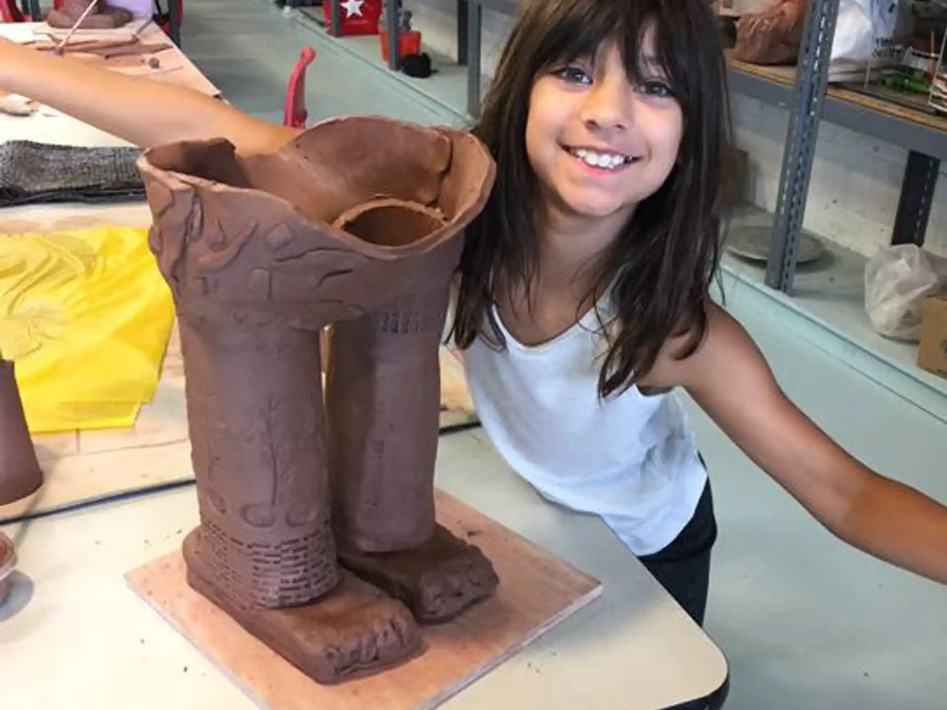 a girl smiling and sitting on a wooden statue of a bear