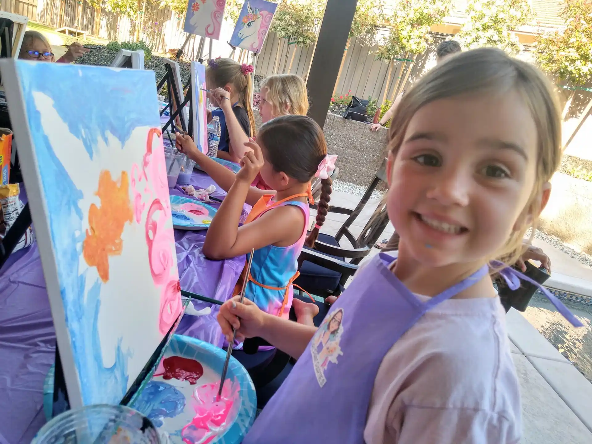 a girl smiling next to a painting