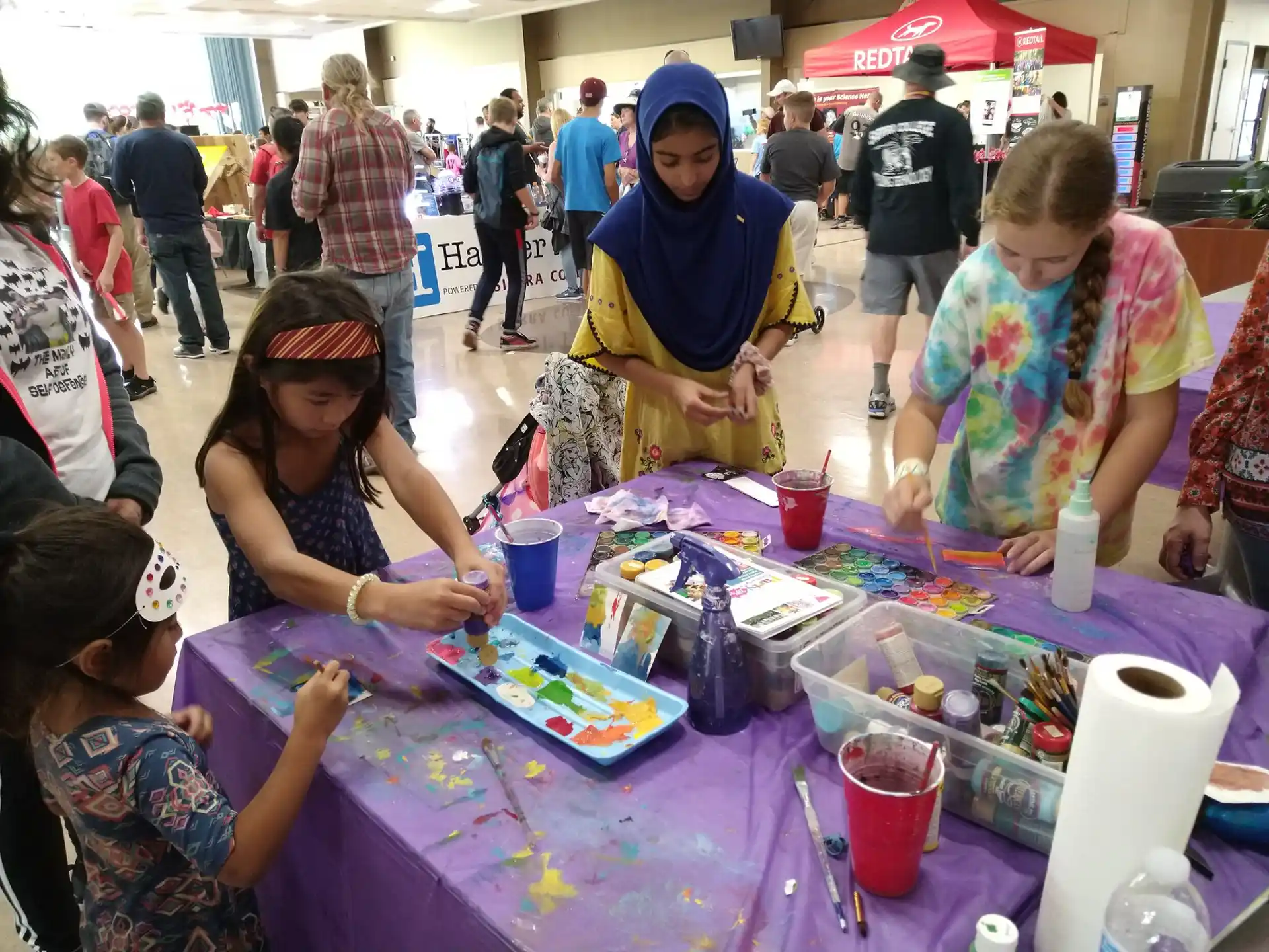 a group of people sitting at a table with a person painting