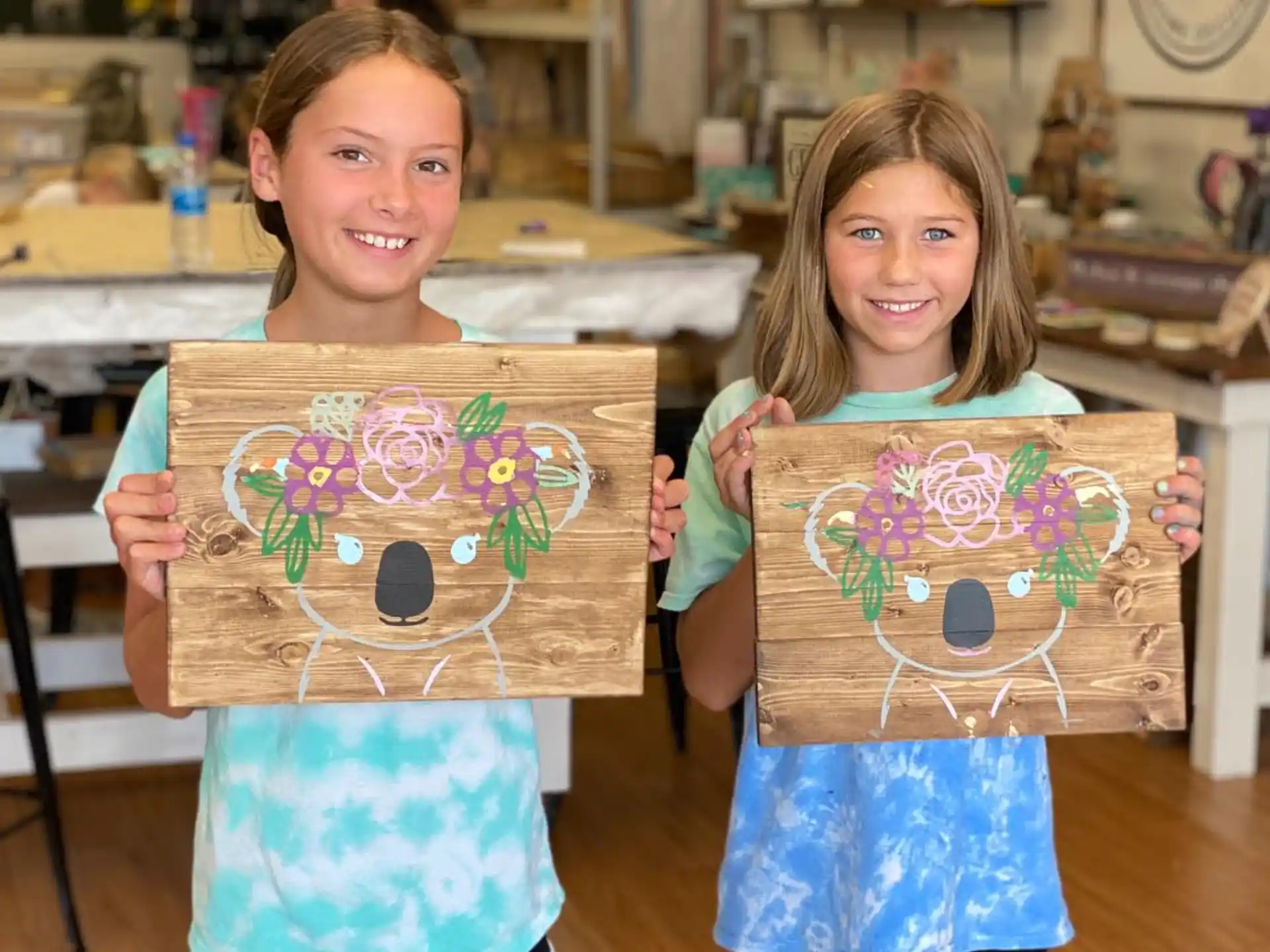 a couple of girls holding up paintings