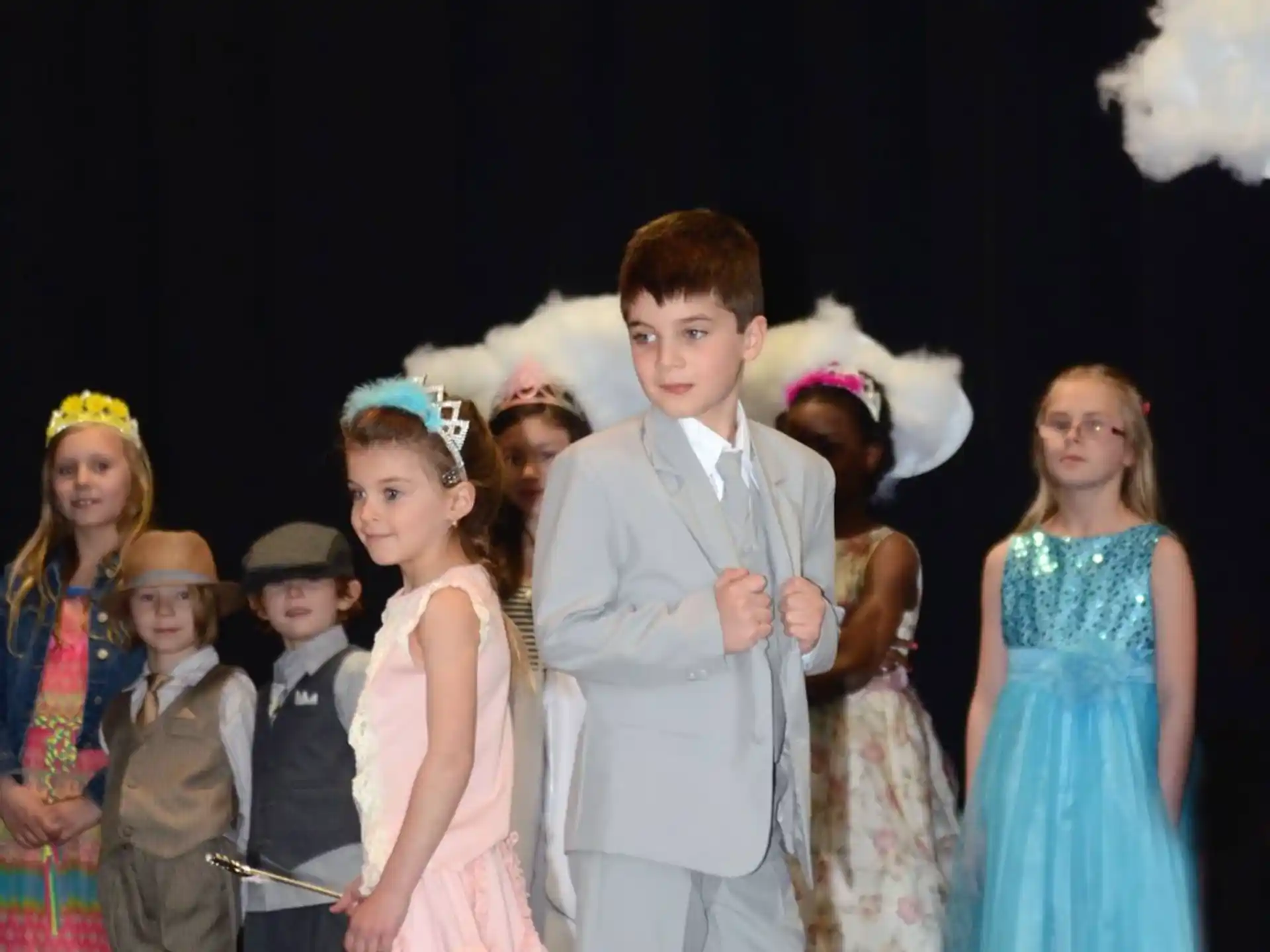 a man in a suit and a group of children on a stage