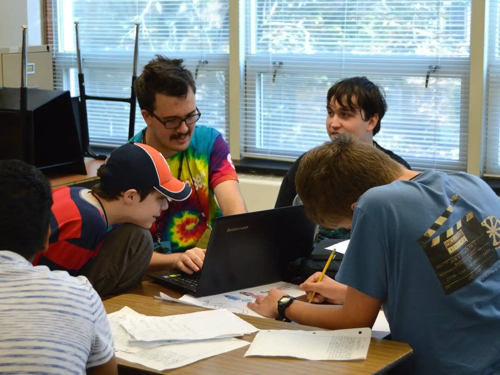 a group of people sitting at a table looking at a laptop