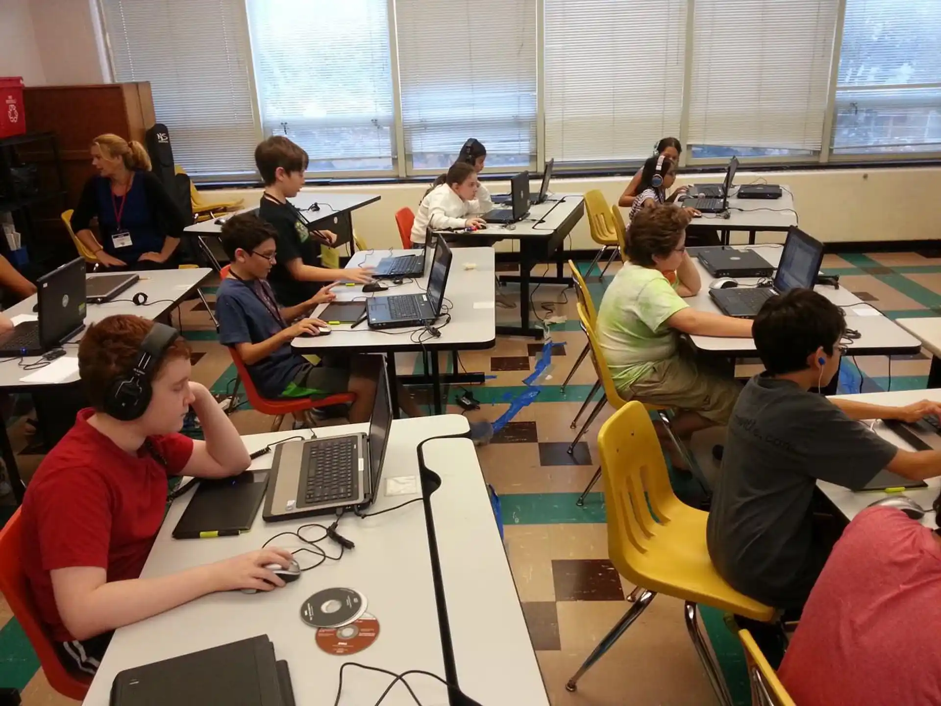 a group of people sitting at desks with laptops