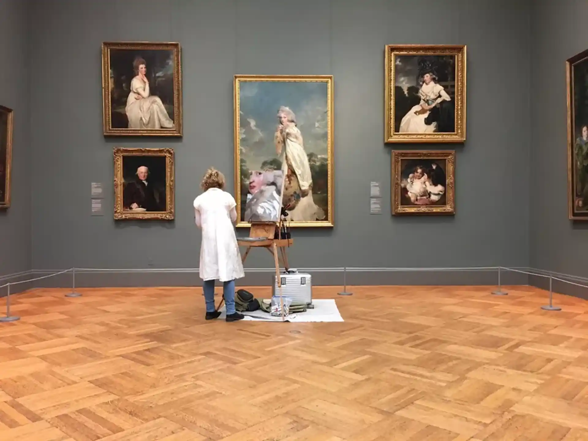 a person standing in front of a wall of paintings