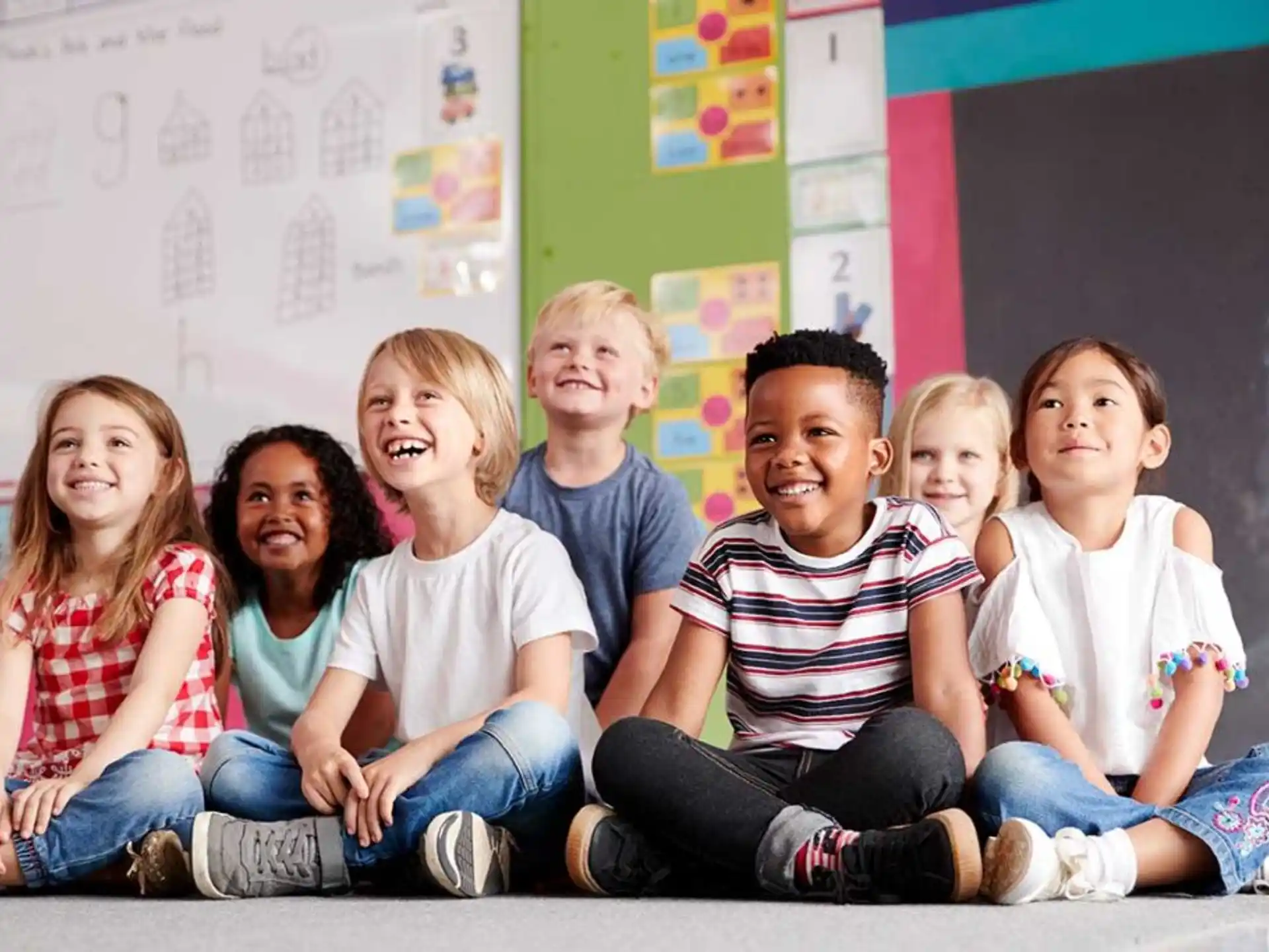 a group of children sitting on the floor smiling for the camera