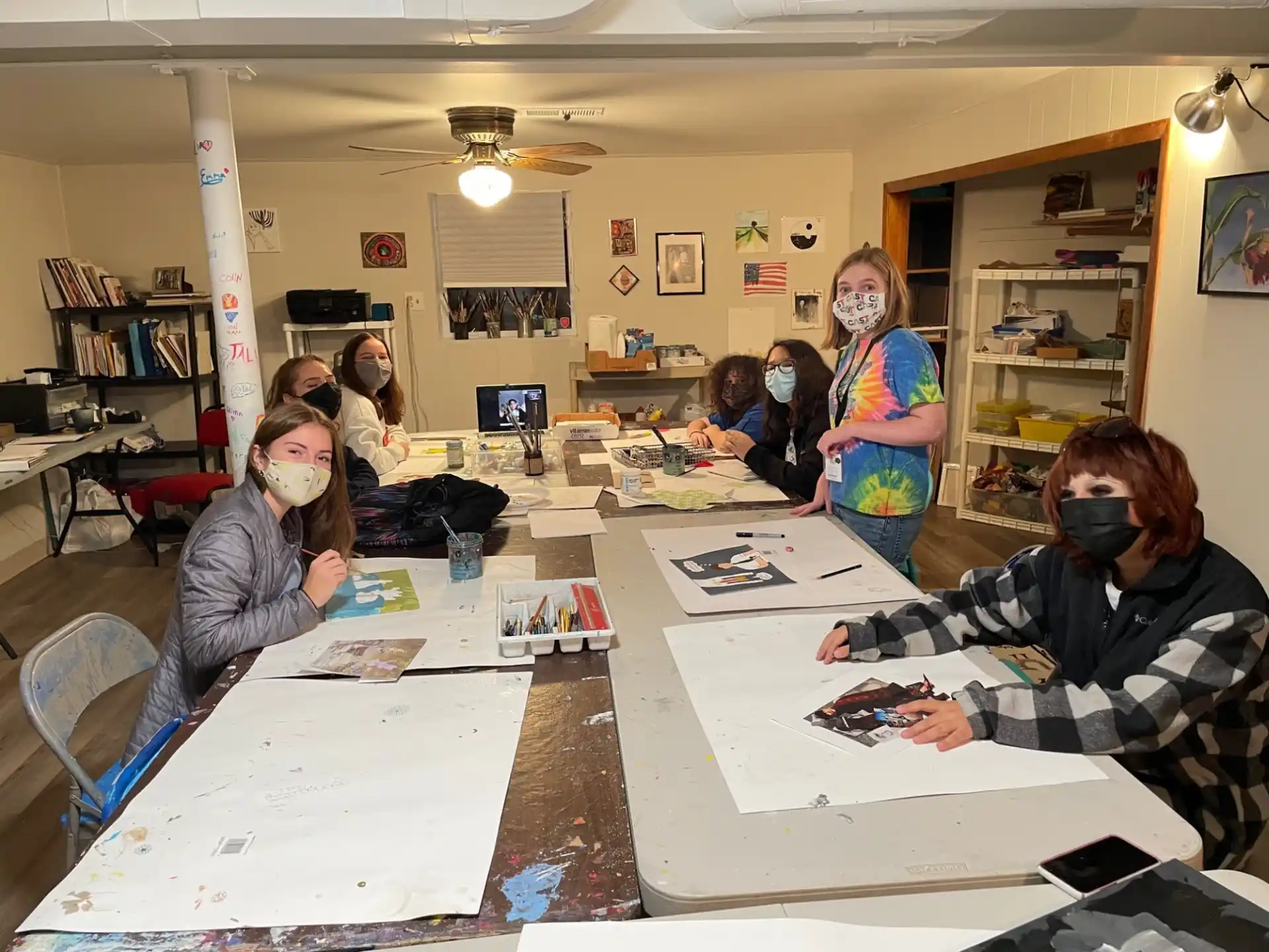 a group of people sitting at a table with masks on