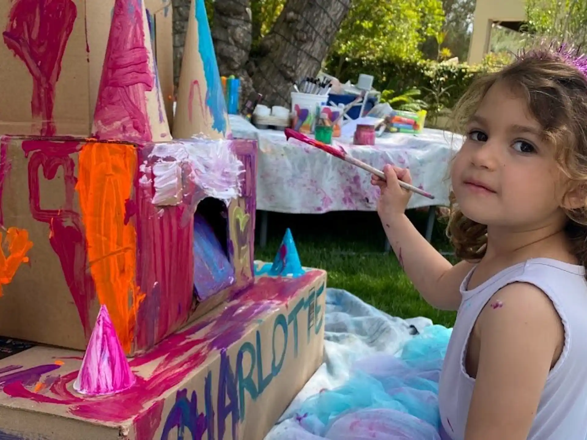 a girl sitting at a table with a birthday cake and a fork