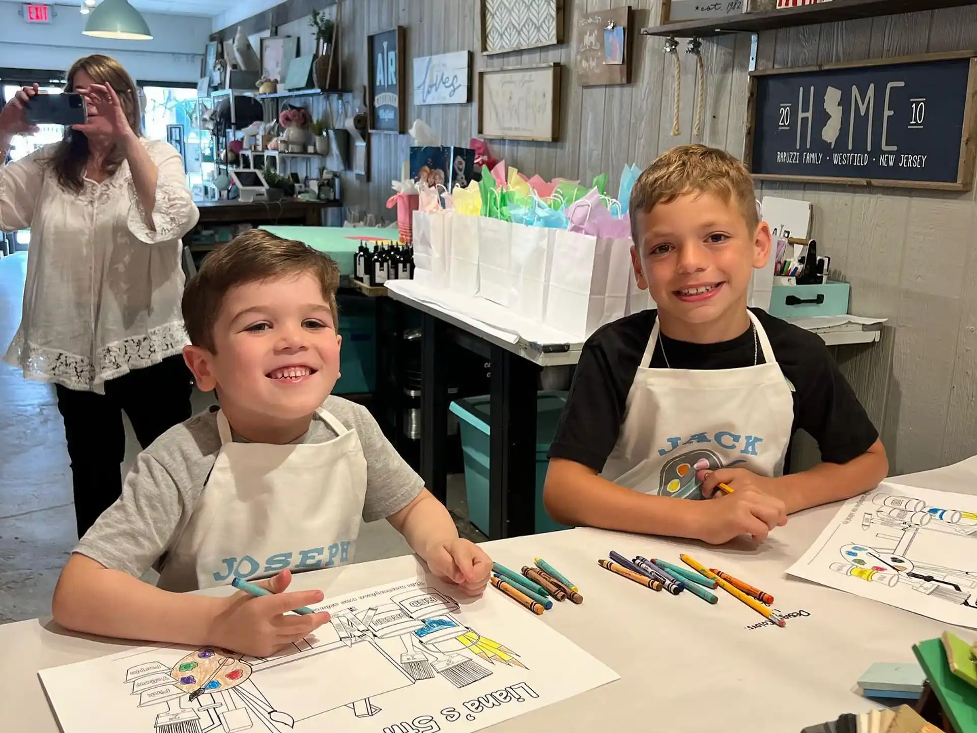 a couple of boys sitting at a table with a drawing