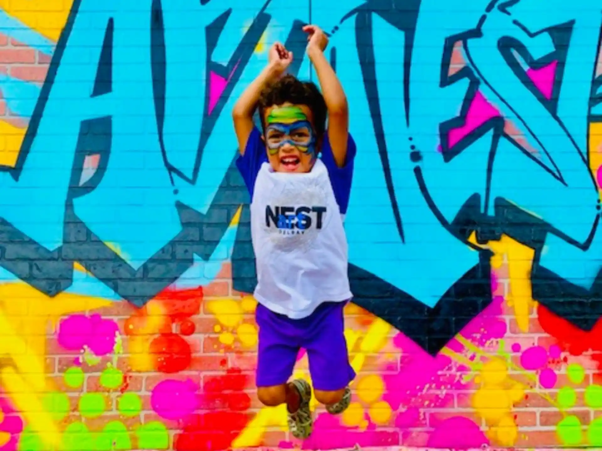 a boy posing in front of a wall covered in graffiti