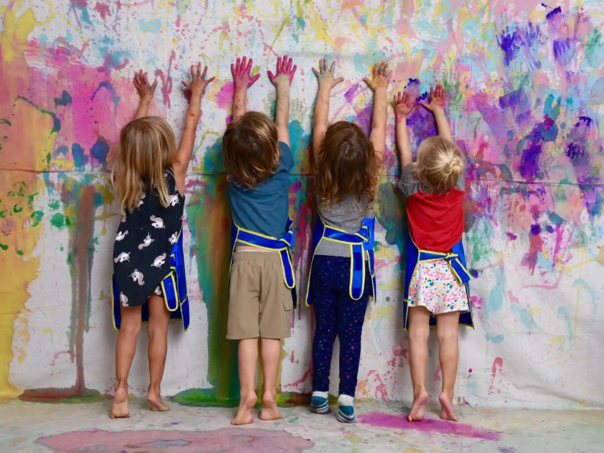 a group of children standing in front of a wall with graffiti