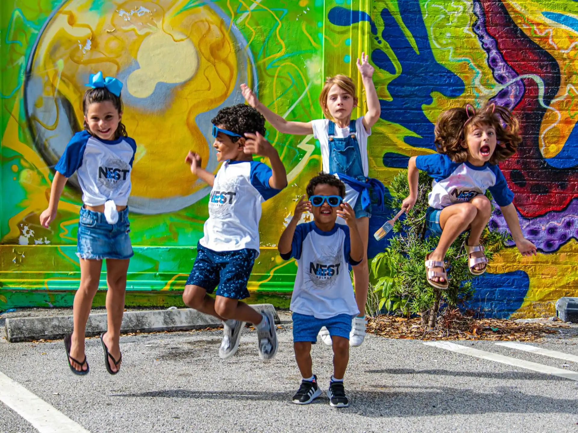 a group of kids jumping in the air in front of a wall