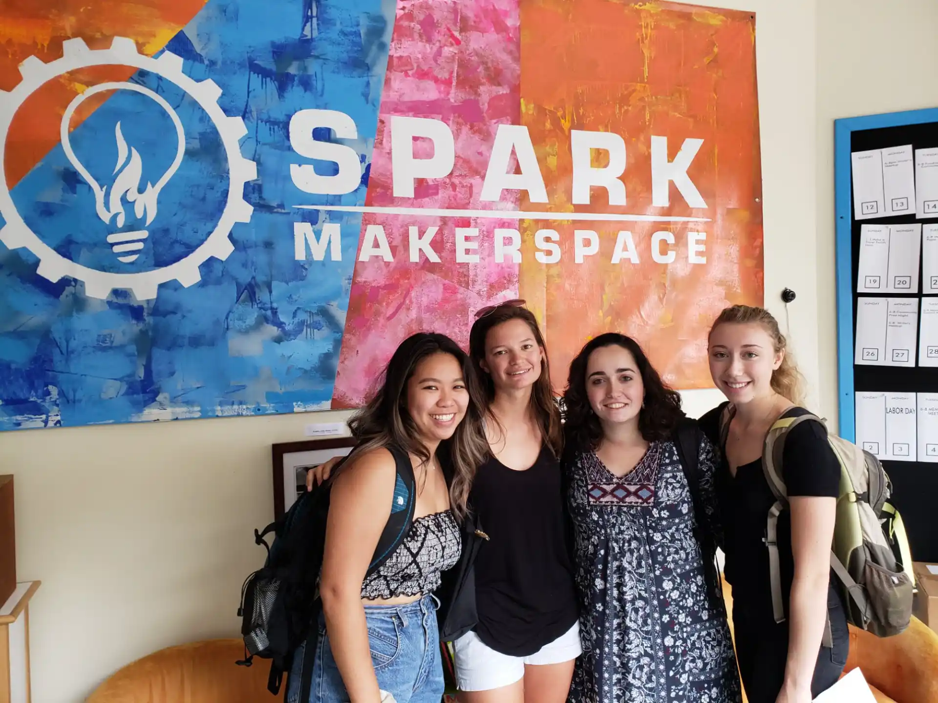 a group of women posing for a photo in front of a sign