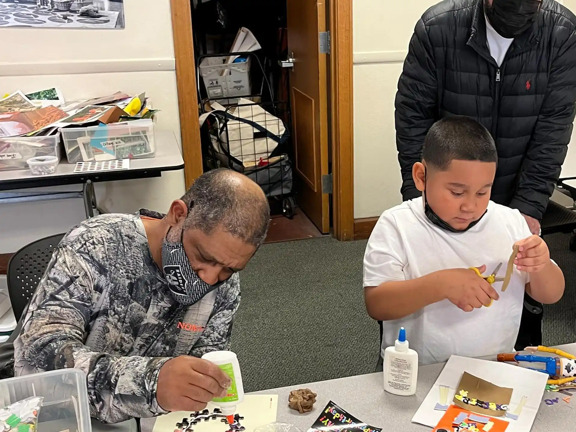a person and a boy sitting at a table with a person standing behind them