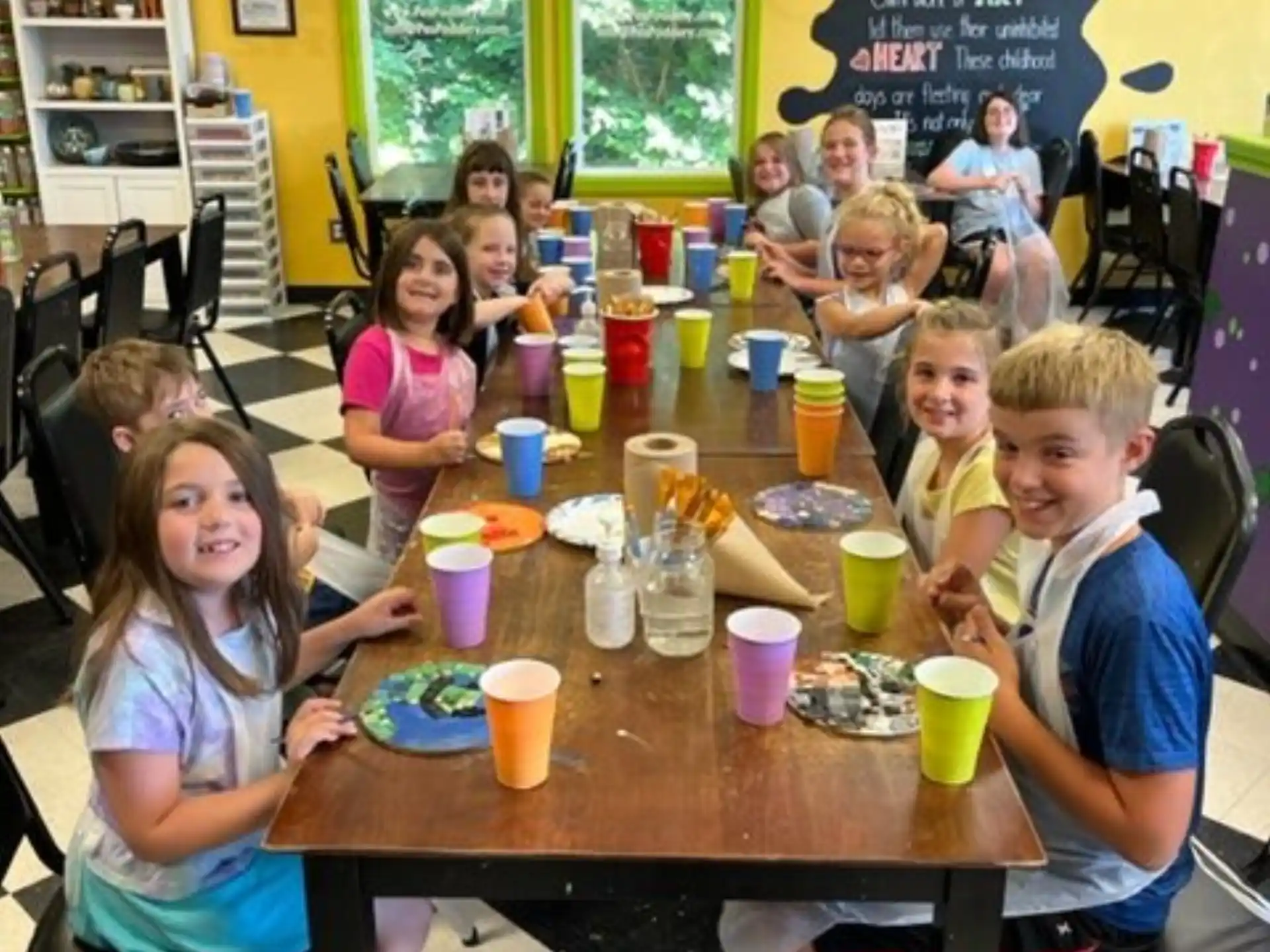 a group of children sitting at a table with food and drinks