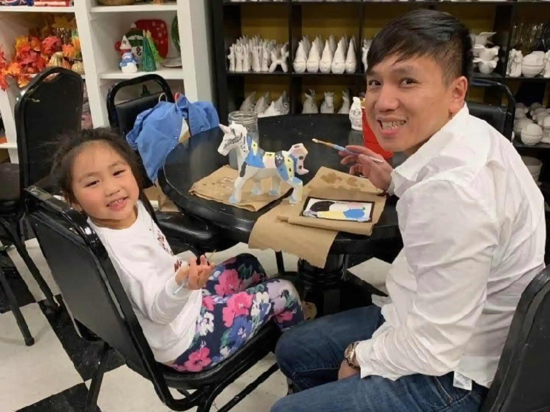 a person and a girl sitting at a table with a book and a book