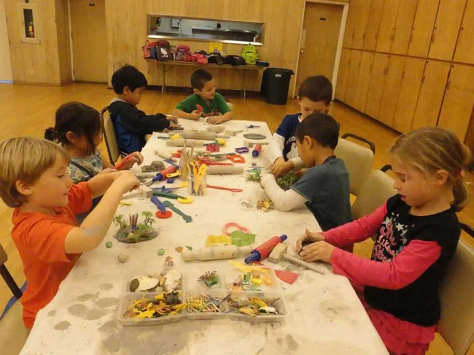 a group of children sitting around a table with toys on it