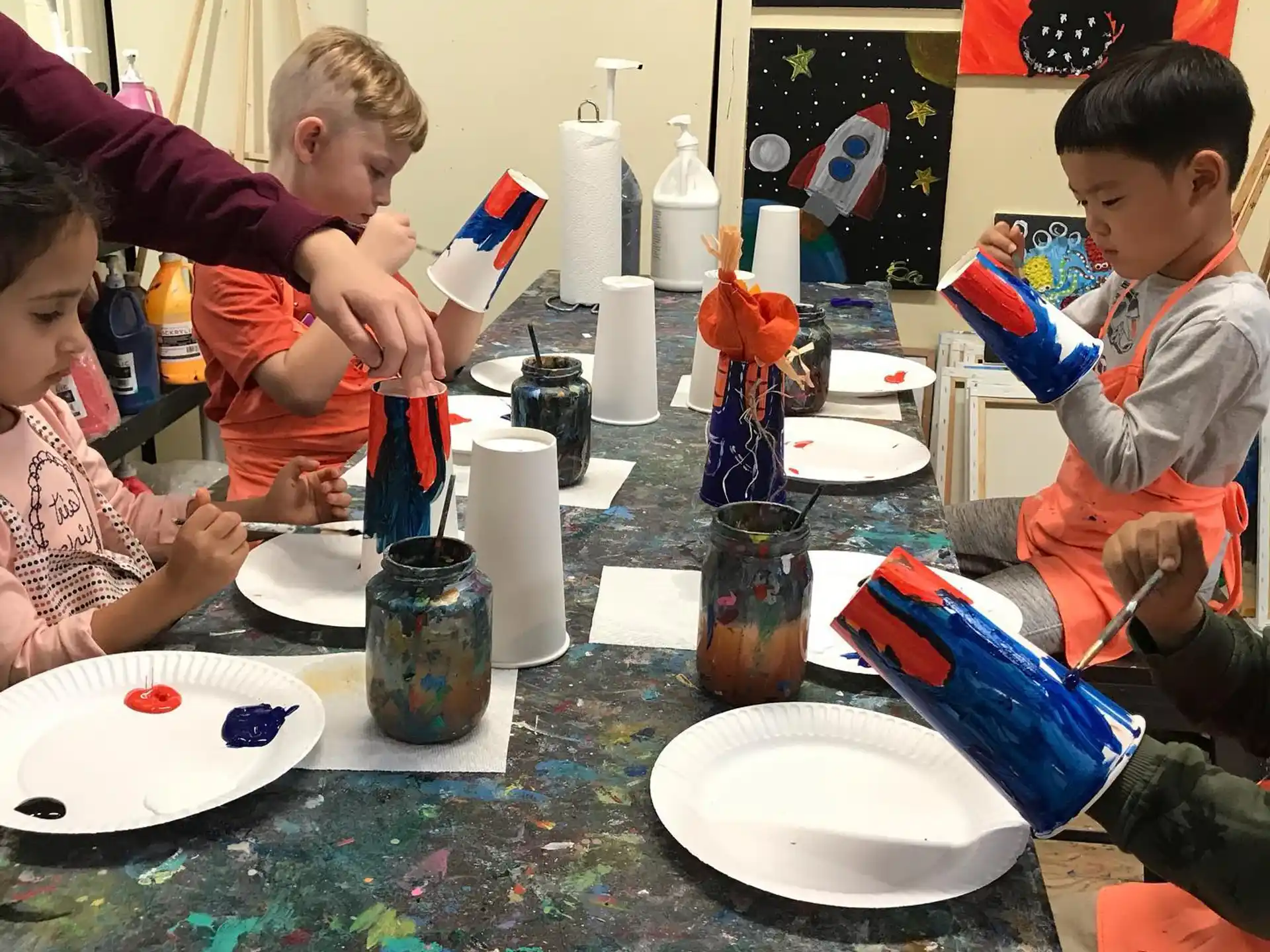 a group of children sitting around a table with plates and cups
