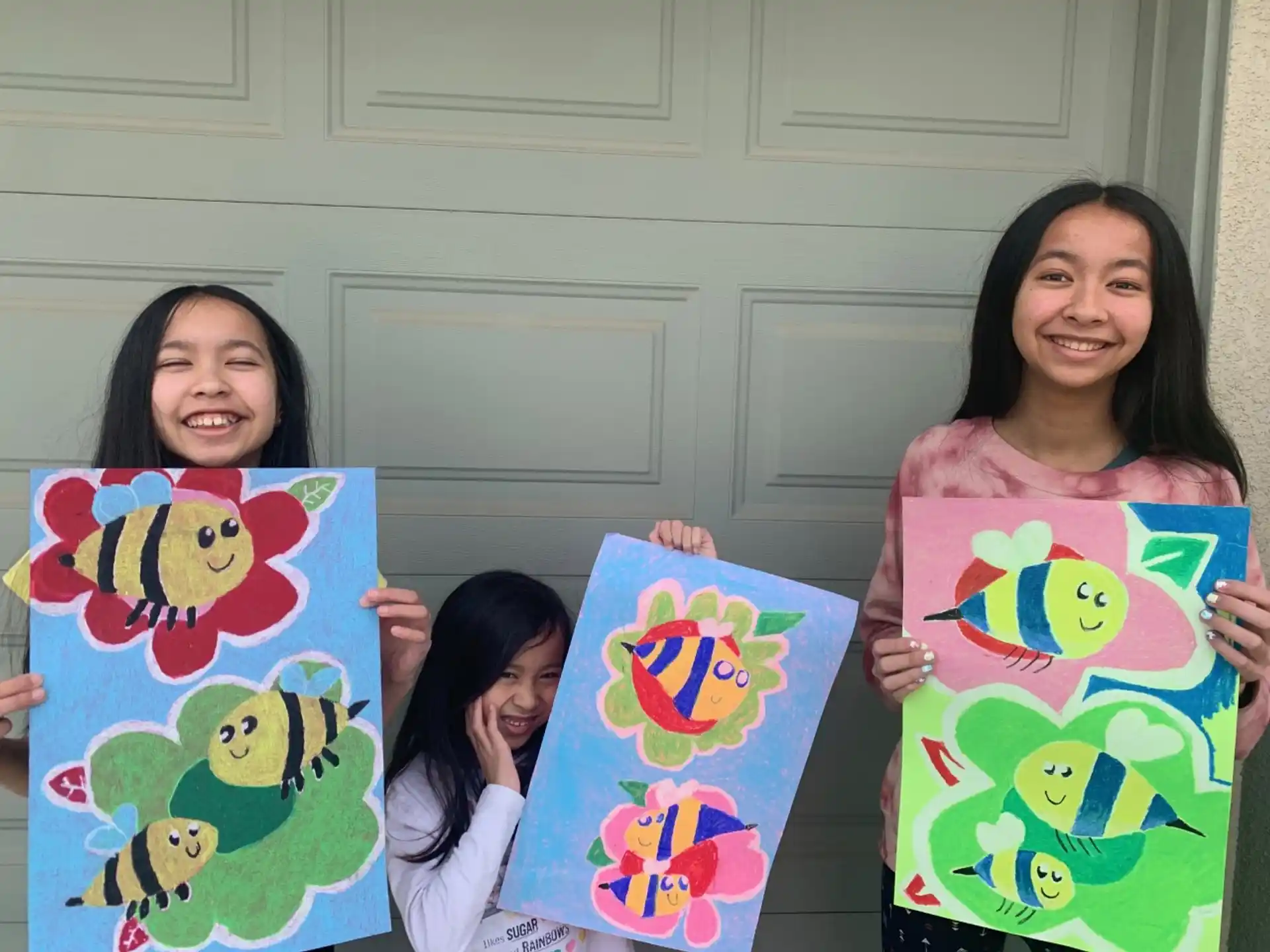 a group of girls holding up paintings