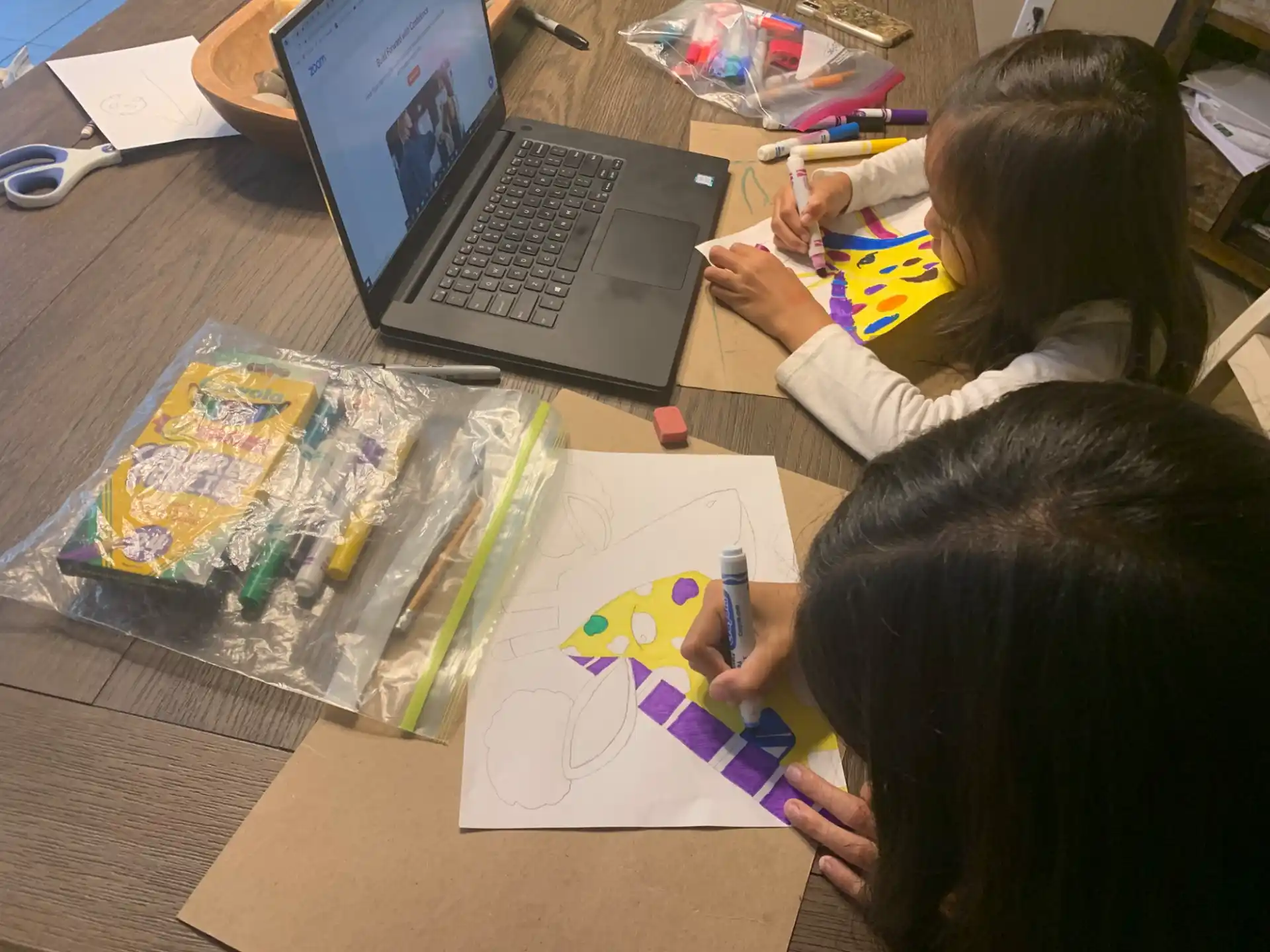children sitting at a table with a laptop and art