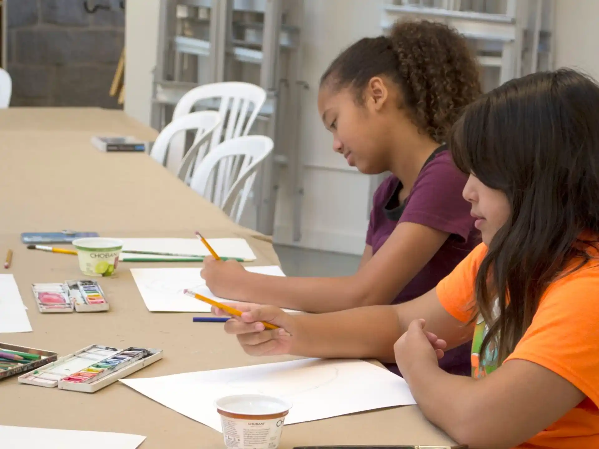 a person and a girl sitting at a table looking at papers