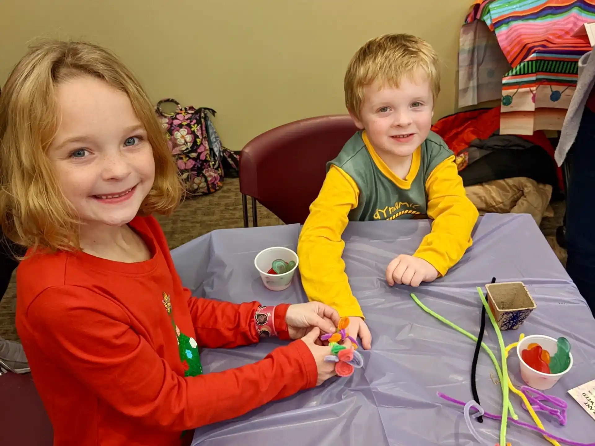 a boy and girl sitting at a table with a toy