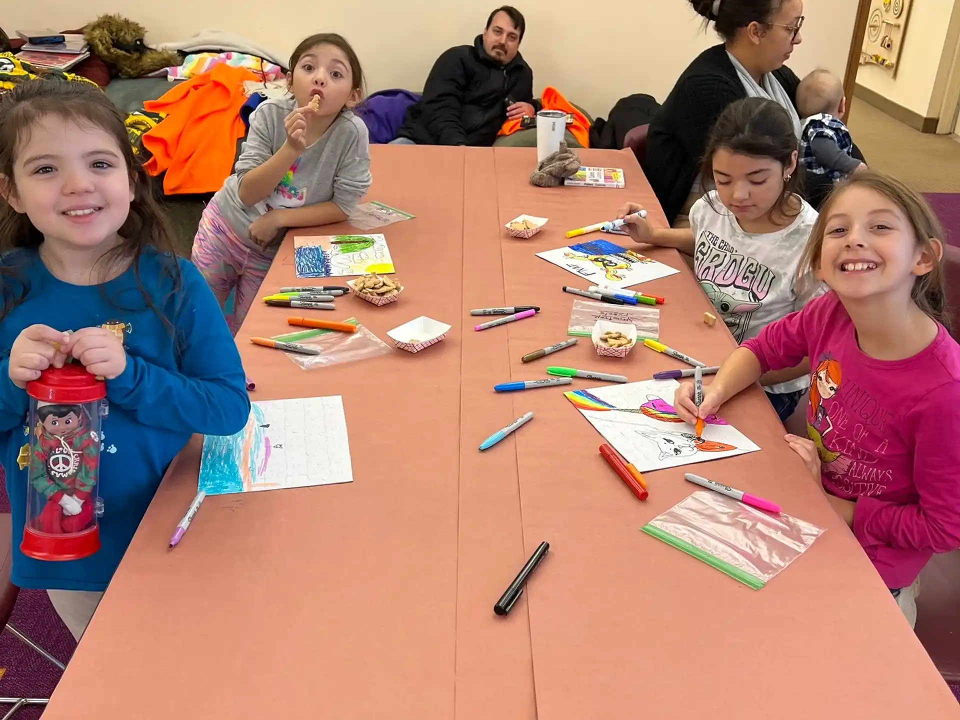 a group of children sitting at a table with books and paper